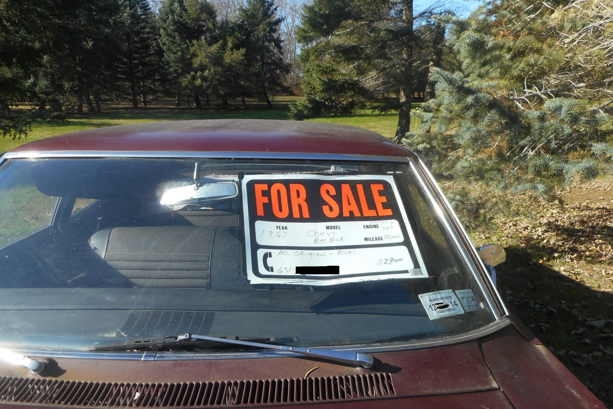 A 'For Sale' sign in the windshield of a 1967 Chevrolet Bel Air, parked on a lawn in Orient Point, New York